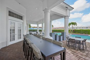 a dining area with a long table and chairs and a pool at The Falls of Portofino Apartment, Naples, FL, 34119